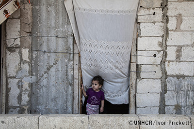 写真:レバノンの建築途中の建物の戸口に立つシリア難民の女の子