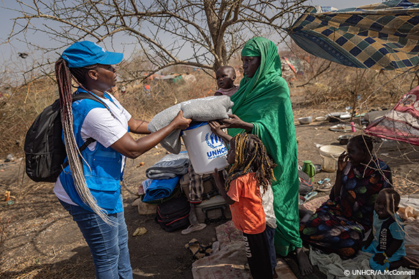 UNHCR職員から救援物資を受け取る人々